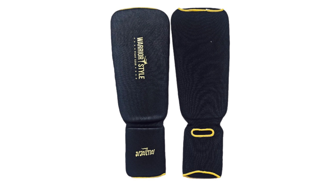Pair of black shin guards with yellow accents on a white background A pair of black and yellow shin guards with hook-and-loop straps a product of https://www.shopwarriorstyle.com/