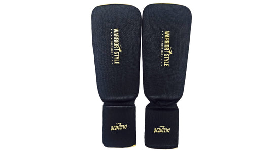 Pair of black shin guards with yellow accents on a white background A pair of black and yellow shin guards with hook-and-loop straps a product of https://www.shopwarriorstyle.com/