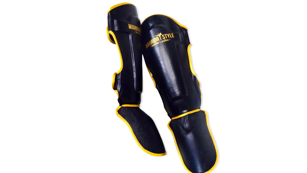 A pair of black and yellow shin guards with hook-and-loop straps a product of https://www.shopwarriorstyle.com/
