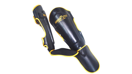 A pair of black and yellow shin guards with hook-and-loop straps a product of https://www.shopwarriorstyle.com/